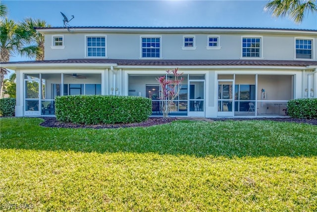 back of property with a sunroom, a lawn, and ceiling fan