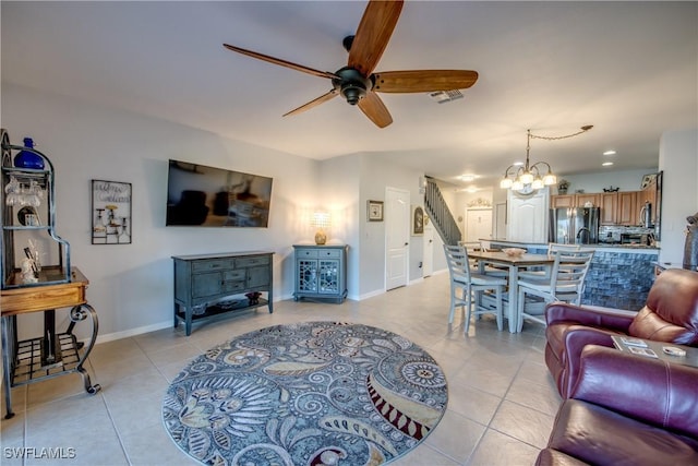 living room with ceiling fan with notable chandelier, visible vents, baseboards, and light tile patterned floors