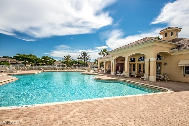 community pool with fence and a patio