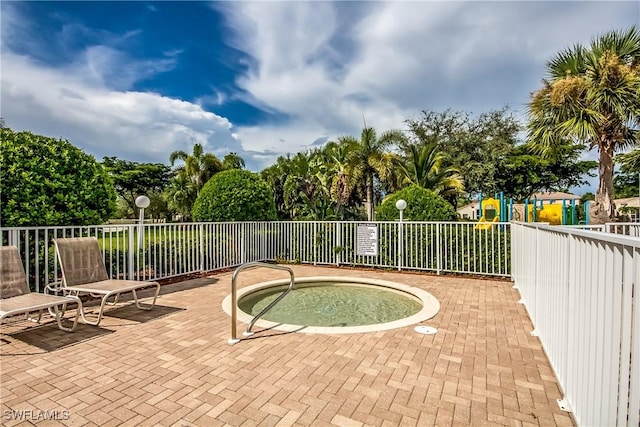 view of swimming pool with a patio area, a hot tub, fence, and playground community