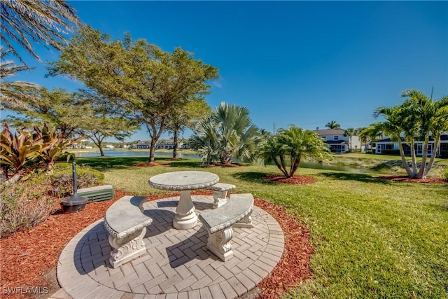 view of property's community featuring a water view, a yard, and a patio