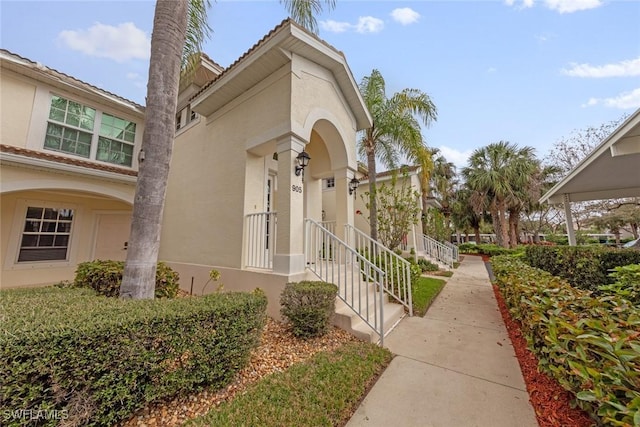 view of exterior entry with a tiled roof and stucco siding