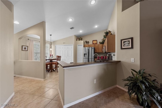 kitchen featuring pendant lighting, brown cabinets, stainless steel appliances, dark countertops, and a peninsula