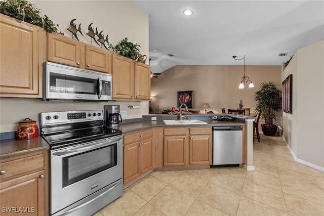 kitchen with dark countertops, appliances with stainless steel finishes, light tile patterned flooring, a sink, and a chandelier