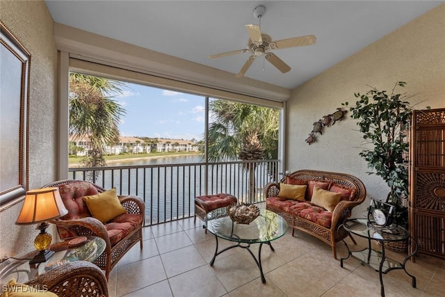 sunroom with ceiling fan and a water view