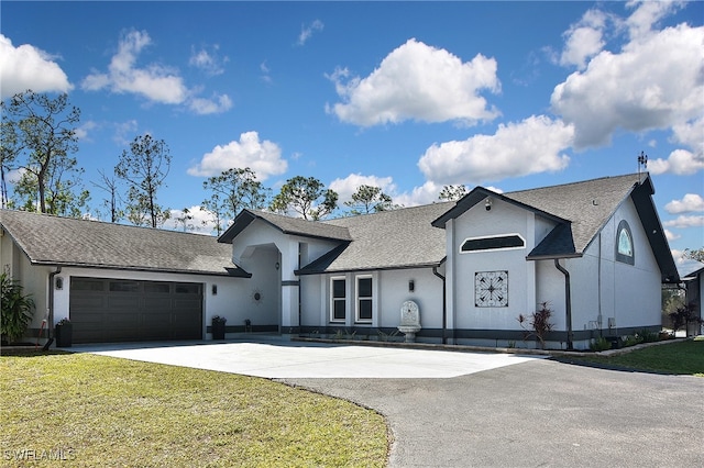 view of front of property featuring an attached garage, a front lawn, concrete driveway, and stucco siding