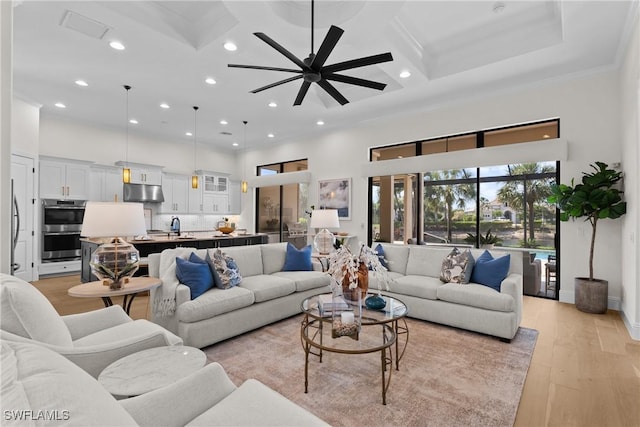 living area with light wood-style floors, a high ceiling, coffered ceiling, and crown molding