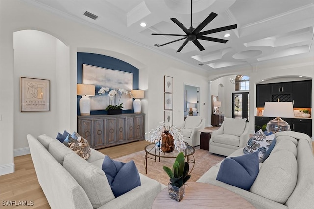 living room featuring ornamental molding, light wood-type flooring, coffered ceiling, and arched walkways