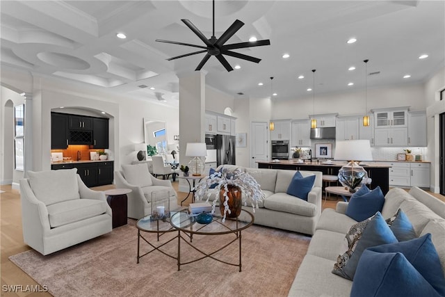 living room featuring arched walkways, recessed lighting, a high ceiling, coffered ceiling, and light wood-style floors