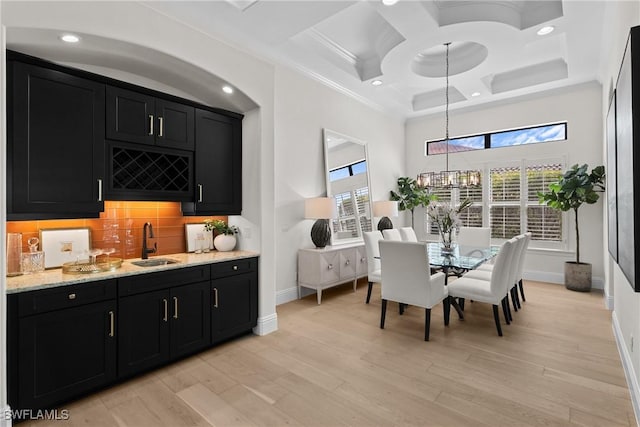 dining area featuring coffered ceiling, a towering ceiling, light wood-type flooring, a chandelier, and indoor wet bar