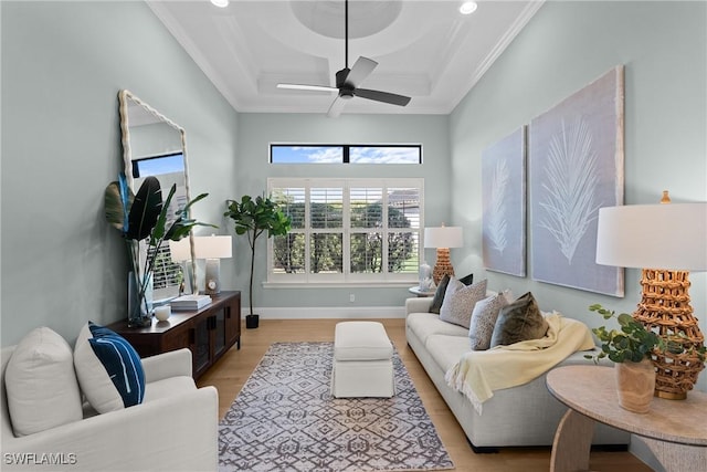 living room featuring light wood-style flooring, coffered ceiling, a ceiling fan, baseboards, and ornamental molding