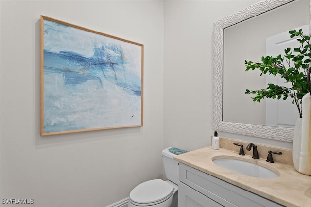 half bath with toilet, baseboards, and vanity