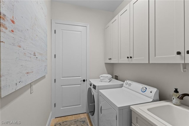 clothes washing area with independent washer and dryer, a sink, and cabinet space