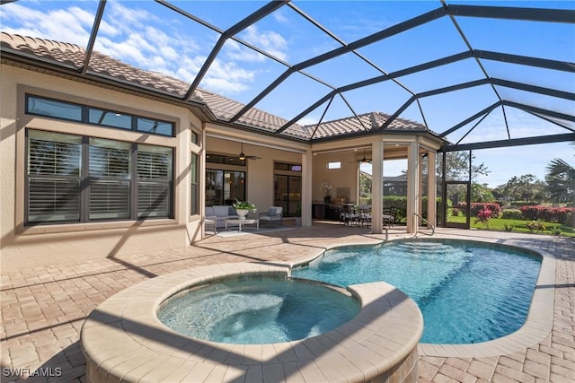 view of swimming pool featuring a pool with connected hot tub, glass enclosure, a patio area, and a ceiling fan