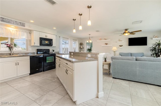 kitchen featuring black appliances, plenty of natural light, open floor plan, and a sink