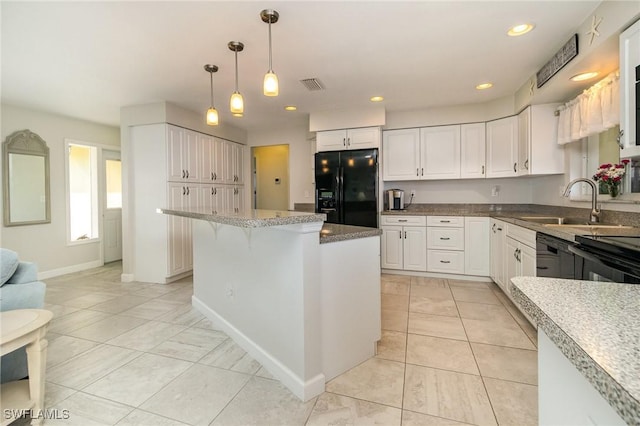 kitchen featuring visible vents, a kitchen breakfast bar, black appliances, white cabinetry, and a sink