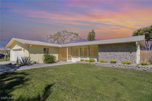 view of front of property featuring stone siding, a lawn, an attached garage, and stucco siding