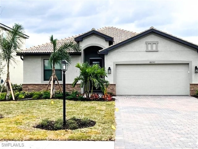 view of front of property with stone siding, an attached garage, decorative driveway, a front lawn, and stucco siding