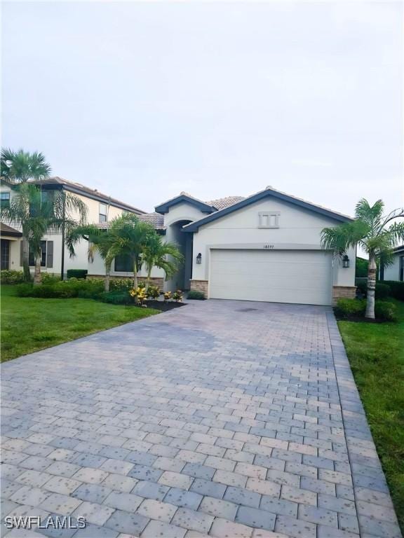 18297 Ridgeline Dr, Estero, FL 33928 - single story home with decorative driveway, an attached garage, stucco siding, and a front lawn