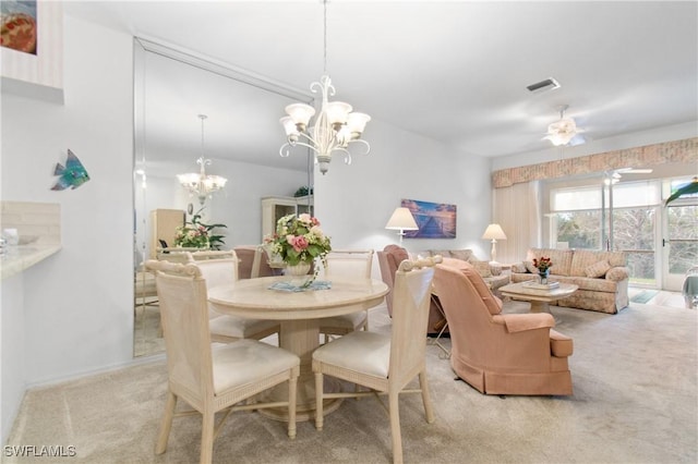 carpeted dining room with visible vents and ceiling fan with notable chandelier