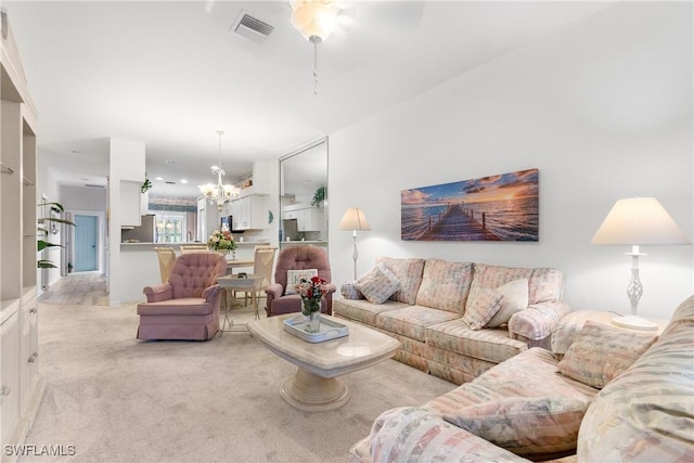 living room featuring light carpet, visible vents, and a notable chandelier