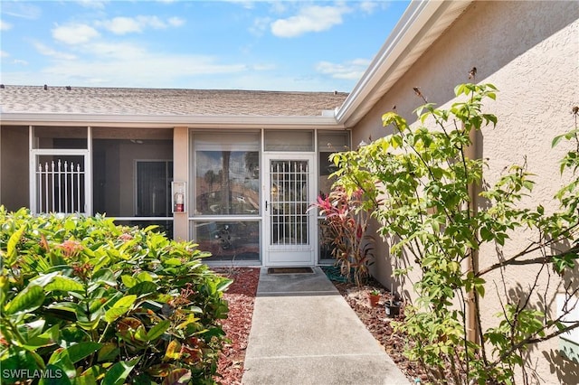 doorway to property with roof with shingles and stucco siding