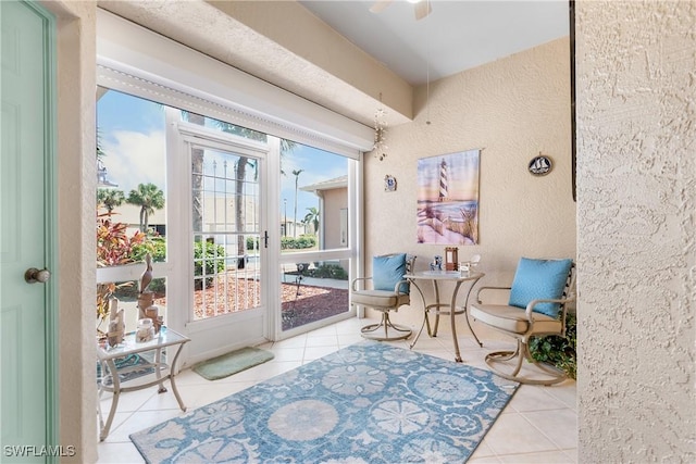 doorway to outside with tile patterned flooring, a ceiling fan, and a textured wall