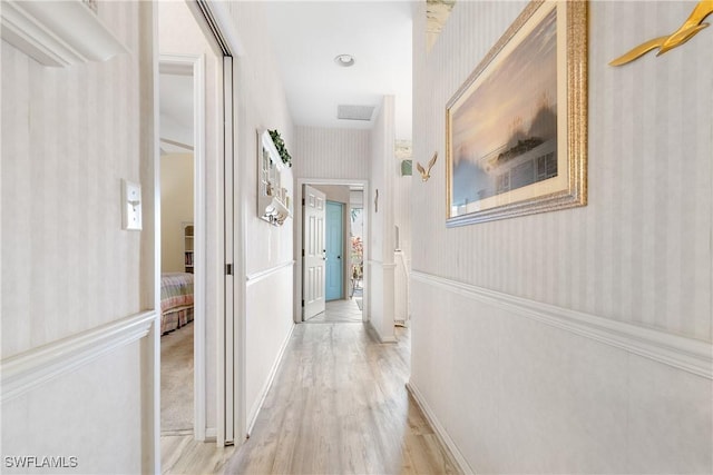 hallway with wallpapered walls and light wood finished floors