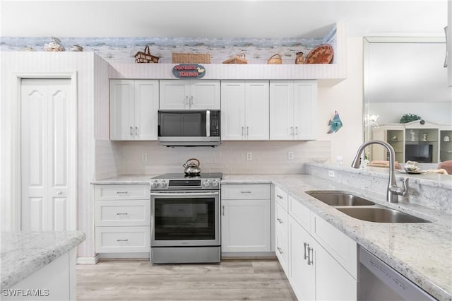 kitchen with stainless steel appliances, light wood-type flooring, a sink, and white cabinets