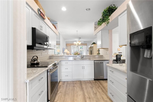 kitchen with decorative backsplash, white cabinets, appliances with stainless steel finishes, light wood-style floors, and a sink