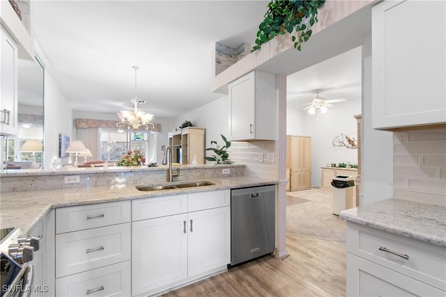 kitchen with appliances with stainless steel finishes, white cabinets, a sink, light stone countertops, and ceiling fan with notable chandelier