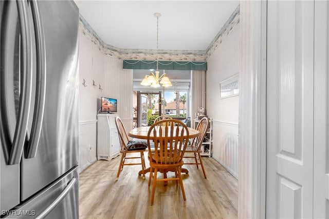 dining area with light wood finished floors and an inviting chandelier