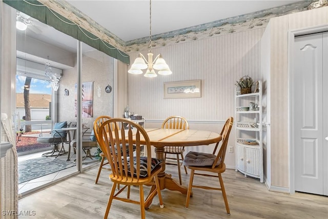 dining area featuring a chandelier, light wood finished floors, and wallpapered walls