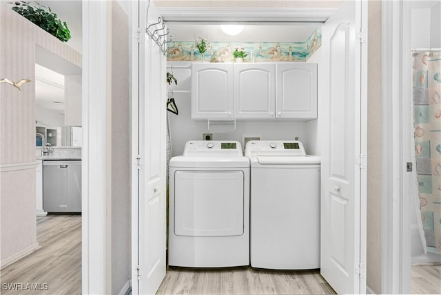 washroom with light wood-style floors, cabinet space, and washing machine and clothes dryer