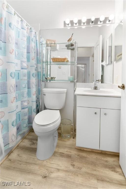 bathroom with toilet, curtained shower, wood finished floors, and vanity