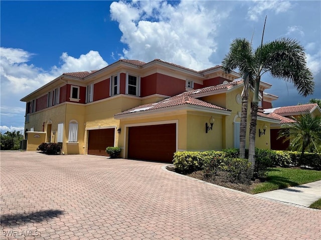 mediterranean / spanish house with decorative driveway, a tiled roof, and stucco siding