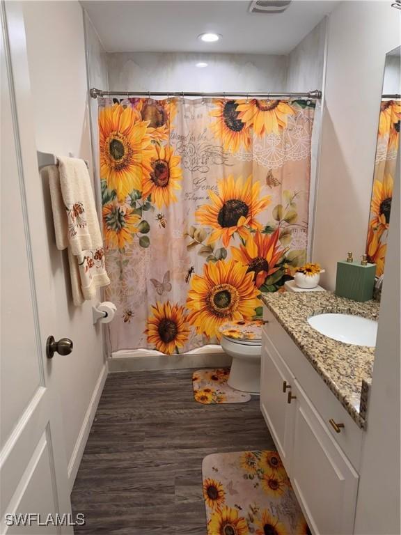 bathroom featuring baseboards, toilet, a shower with curtain, wood finished floors, and vanity