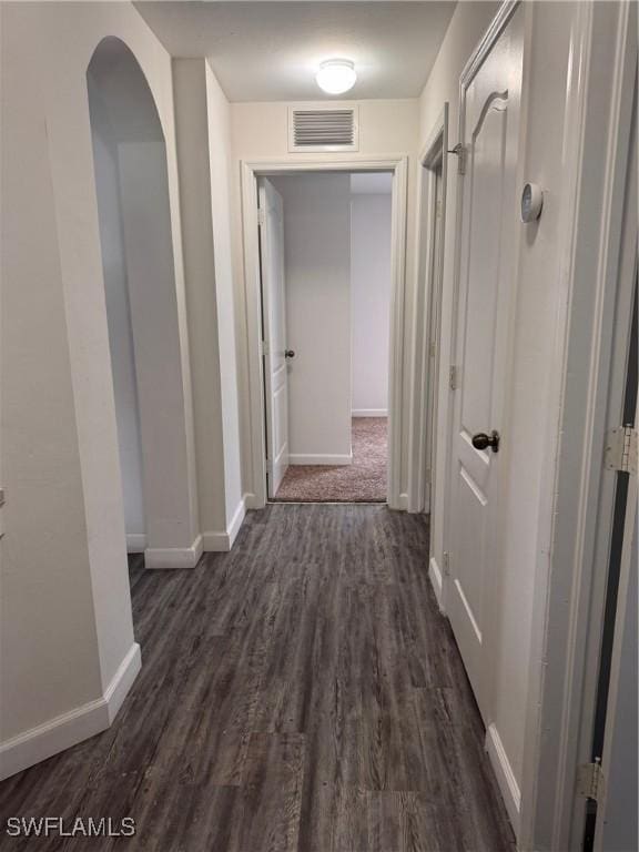 hall featuring dark wood-style floors, baseboards, and visible vents