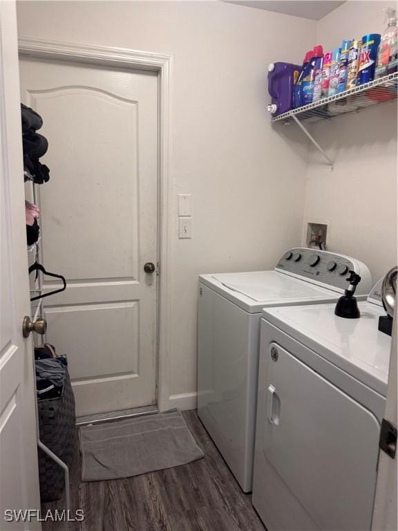 clothes washing area with laundry area, washer and clothes dryer, and dark wood finished floors