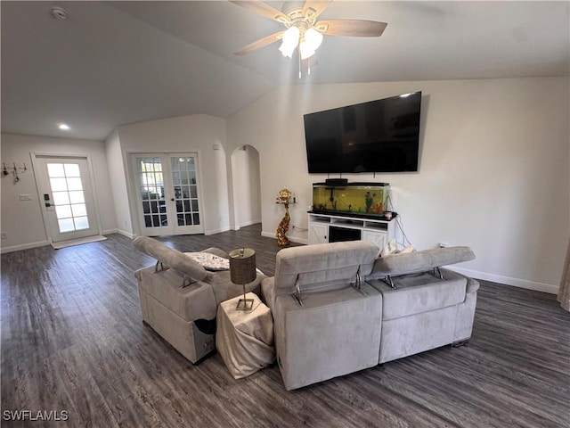 living area with lofted ceiling, arched walkways, and dark wood finished floors