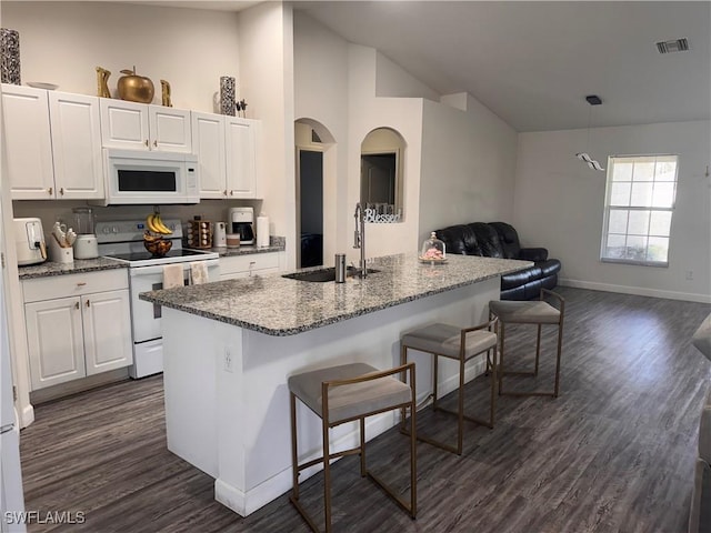 kitchen featuring white appliances, white cabinetry, a breakfast bar, and a sink