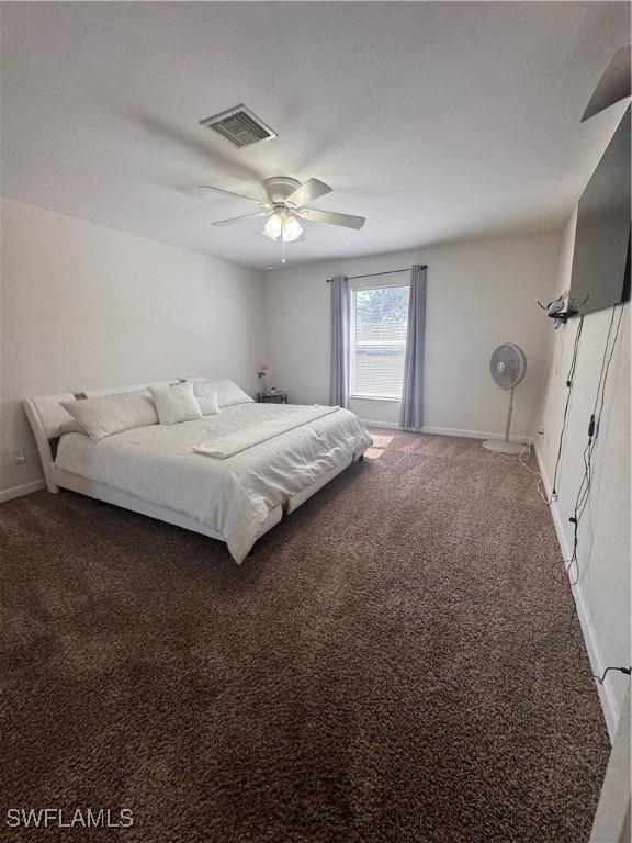 bedroom with dark colored carpet, a ceiling fan, visible vents, and baseboards