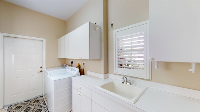 laundry room with washing machine and clothes dryer, a sink, and cabinet space