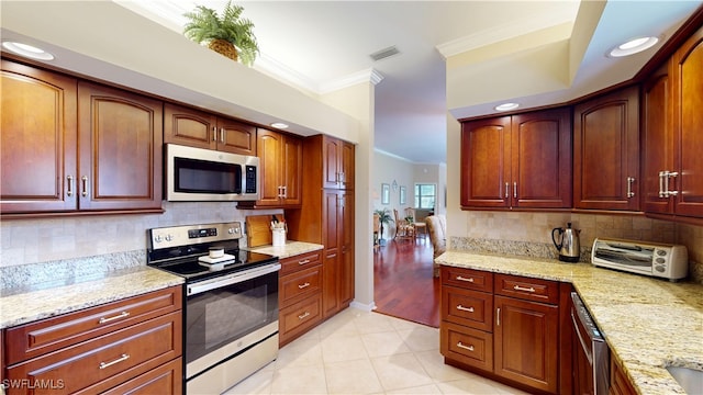 kitchen featuring a toaster, crown molding, decorative backsplash, appliances with stainless steel finishes, and light stone countertops