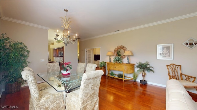 dining area featuring crown molding, baseboards, wood finished floors, and a notable chandelier