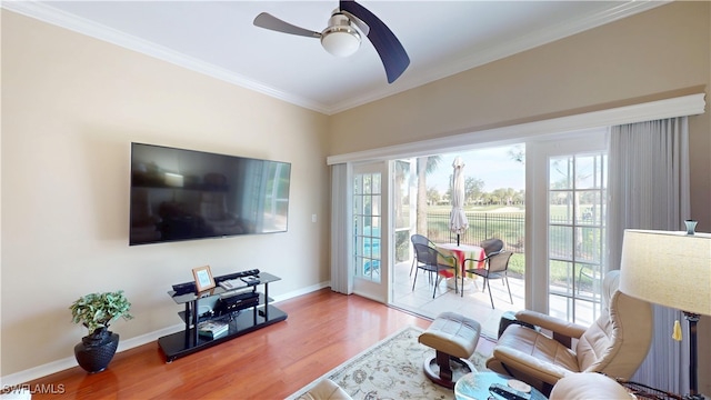 living room featuring baseboards, ornamental molding, wood finished floors, and a healthy amount of sunlight