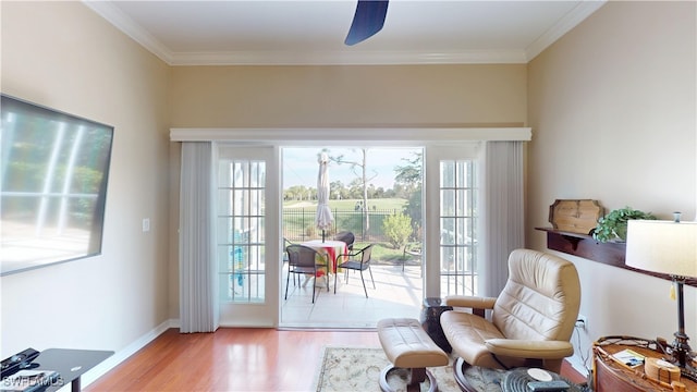 sitting room featuring plenty of natural light, light wood-style flooring, baseboards, and crown molding