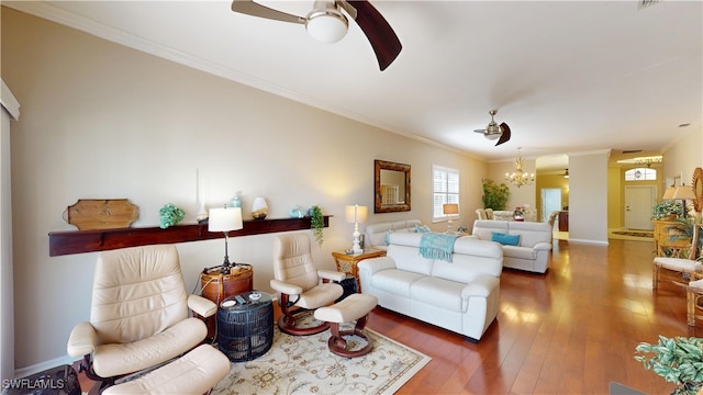 living room with baseboards, ornamental molding, dark wood-type flooring, and ceiling fan with notable chandelier