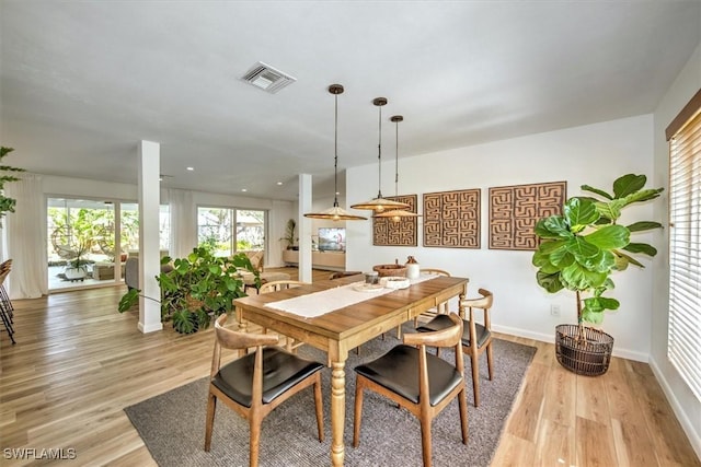 dining area featuring a healthy amount of sunlight, visible vents, and light wood-style flooring