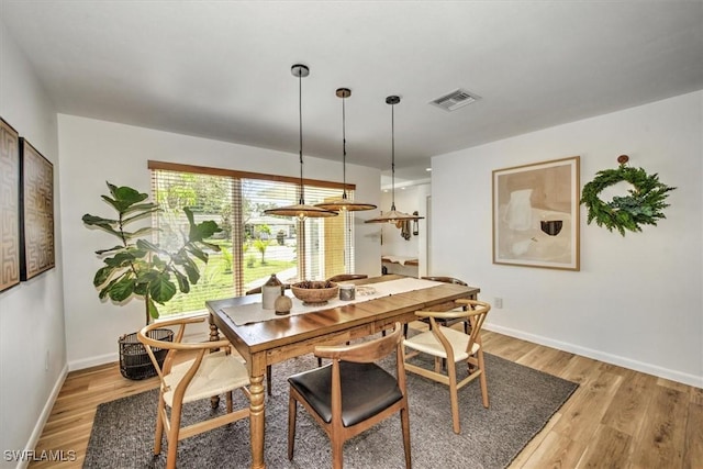 dining room with light wood-style flooring, visible vents, and baseboards